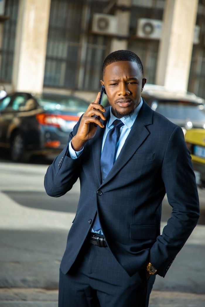 why-choose-us Confident businessman in formal attire making a phone call outdoors in Dakar, Senegal.